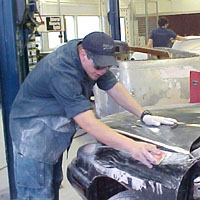 Student wet sands a panel.